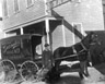 Man carrying a basket of bread in front of Zazzalis Bakery Wagon